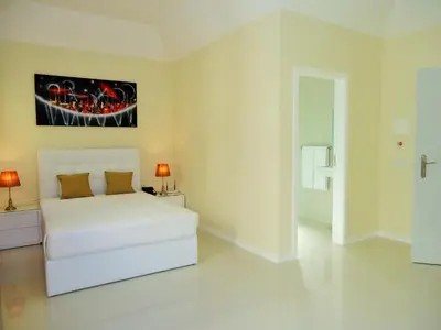 a white bedroom with a bed and a painting on the wall at São Francisco Accommodation in Funchal