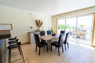 a dining room with a table and black chairs at Infinite Ocean View Villa 20m above Ocean & Beach in Arco da Calheta