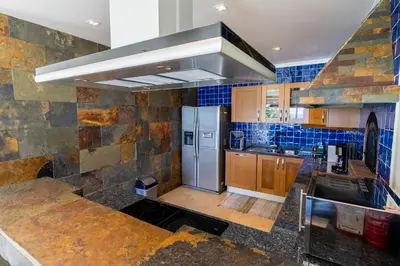 a kitchen with a stainless steel refrigerator and blue tiles at Infinite Ocean View Villa 20m above Ocean & Beach in Arco da Calheta