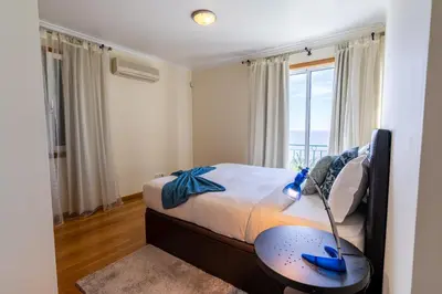 a bedroom with a bed with a table and a window at Infinite Ocean View Villa 20m above Ocean & Beach in Arco da Calheta