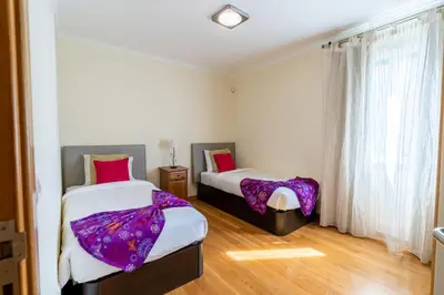 two beds in a room with wooden floors at Infinite Ocean View Villa 20m above Ocean & Beach in Arco da Calheta