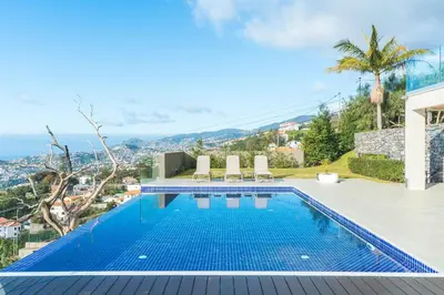 a swimming pool with two chairs on top of a house at Eco Monte by Atlantic Holiday in Funchal