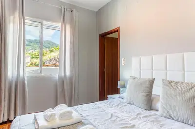 a bedroom with a white bed and a window at Estrela House I Calheta Madeira in Calheta
