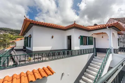 a white house with green shutters and a balcony at Estrela House I Calheta Madeira in Calheta
