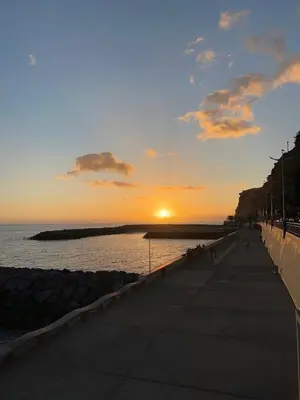 a sunset over a beach with the sun setting over the water at Estrela House I Calheta Madeira in Calheta