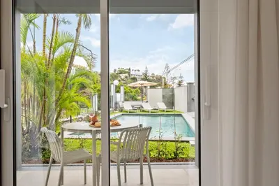 a patio with a table and chairs and a pool at Modern Flat Just Steps From Shore in Ponta do Sol
