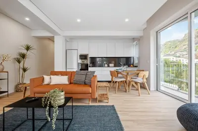 a living room with a couch and a table at Modern Flat Just Steps From Shore in Ponta do Sol