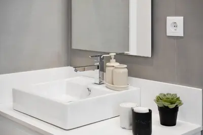 a bathroom with a white sink and a mirror at Modern Flat Just Steps From Shore in Ponta do Sol
