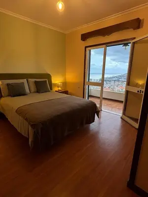 a bedroom with a large bed and a large window at Panoramic Funchal View - 3BR Two-Storey Home in Funchal