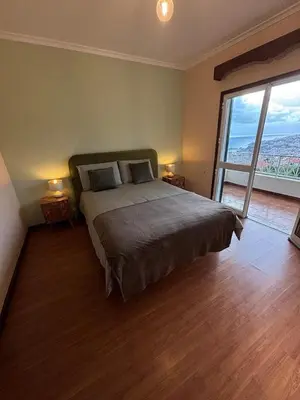 a bedroom with a large bed and a large window at Panoramic Funchal View - 3BR Two-Storey Home in Funchal