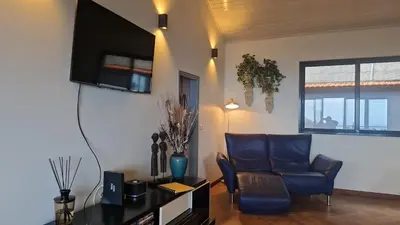 a living room with a couch and a tv at Villa da Rochinha - Luxusapartment mit Atlantikblick in São Roque do Faial