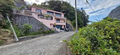 a pink house on the side of a mountain at Villa da Rochinha - Luxusapartment mit Atlantikblick in São Roque do Faial