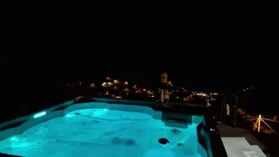 a hot tub at night with a city in the background at Villa da Rochinha - Luxusapartment mit Atlantikblick in São Roque do Faial