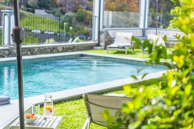 a swimming pool with a table and chairs in a yard at Modern Apartment Steps From Beach in Ponta do Sol
