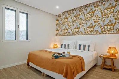 a bedroom with a large bed with a orange blanket at Modern Apartment Steps From Beach in Ponta do Sol