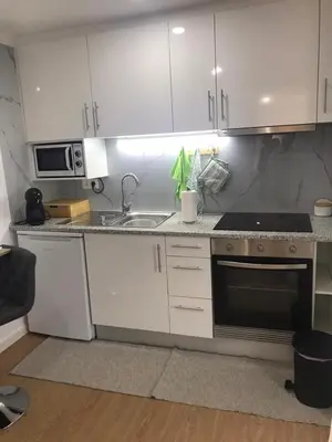 a kitchen with white cabinets and a sink and a microwave at Vivenda Silva in Seixal