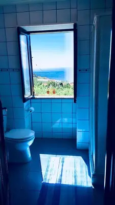 a blue bathroom with a window and a toilet at Sea View Villa in Calheta