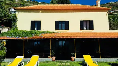 a house with yellow lounge chairs in front of it at Sea View Villa in Calheta