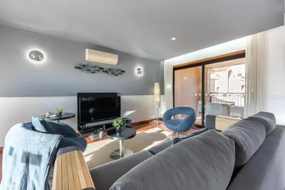a living room with a gray couch and a tv at Baia da Luz - Upper Luz Suite in Luz