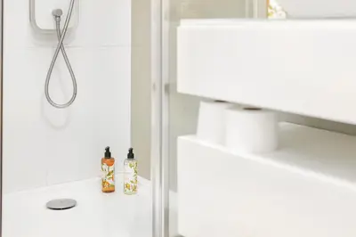 a white bathroom with a shower and two bottles on a counter at Premium Avenue Two Bedrooms Apt in Funchal