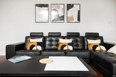 a living room with a black leather couch and a table at Premium Avenue Two Bedrooms Apt in Funchal