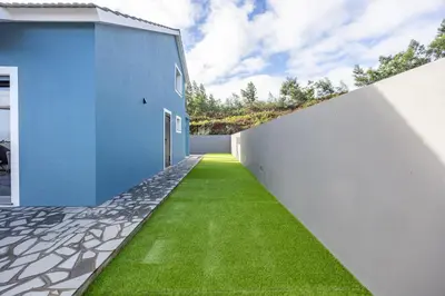 a hallway with green grass next to a white wall at Santana Trail House - Pico Ruivo in Santana