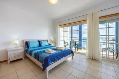 a bedroom with a bed and a large window at Lote 14 Fontainhas in Luz
