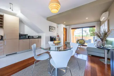 a kitchen and living room with a glass table and white chairs at Baia da Luz - Luz Suite in Luz