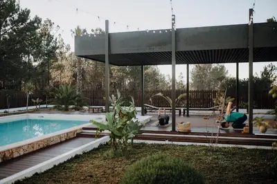 a woman is sitting by a swimming pool at Surf & Yoga Retreats Portugal in Aljezur