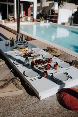a table with plates of food next to a swimming pool at Surf & Yoga Retreats Portugal in Aljezur