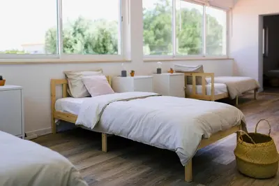 a bedroom with two beds and two windows at Surf & Yoga Retreats Portugal in Aljezur