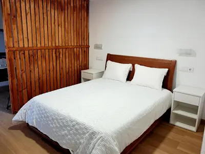 a bedroom with a white bed with a wooden headboard at Casa Noronha 1 in Caniço