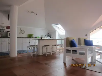a kitchen with white cabinets and a table and chairs at Penthouse Marina Sol in Madalena do Mar