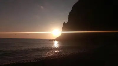 a sunset over the ocean near a cliff at Penthouse Marina Sol in Madalena do Mar