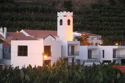 a white building with a clock tower at night at Penthouse Marina Sol in Madalena do Mar
