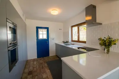a kitchen with white counters and a blue door at Cabasina Bordeira in Bordeira