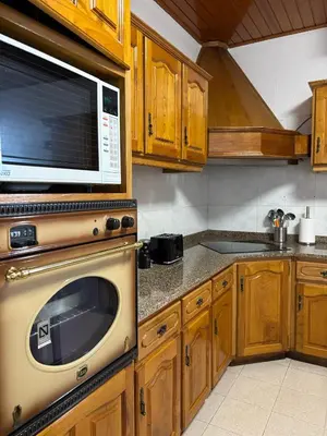a kitchen with wooden cabinets and a microwave at Casa estrelicia II in Relógio do Poiso