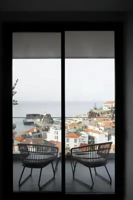 two chairs sitting on a balcony looking out at the ocean at B View Madeira - Ocean & Bay View Apartment in Câmara de Lobos