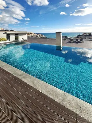 a swimming pool on top of a building with the ocean at B View Madeira - Ocean & Bay View Apartment in Câmara de Lobos