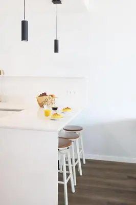 a kitchen with a white counter and stools at B View Madeira - Ocean & Bay View Apartment in Câmara de Lobos
