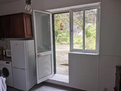 a kitchen with a refrigerator and an open door at Ape T0 in São Vicente