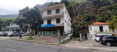 a white building with cars parked in a parking lot at Ape T0 in São Vicente