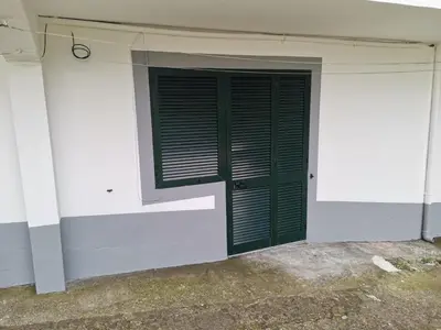 a green door on the side of a white building at Ape T0 in São Vicente