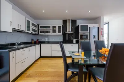 a kitchen with white cabinets and a table with chairs at Oceanfront Villa with Private Pool Breathtaking Sunsets in Madeira in Tábua