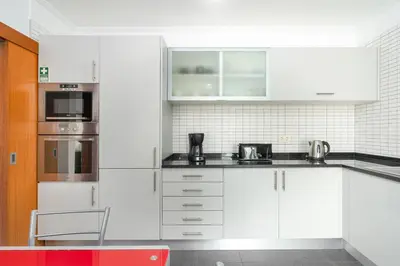 a kitchen with white cabinets and stainless steel appliances at Anchored in Carmo by Homie in Câmara de Lobos