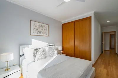 a bedroom with a white bed and a wooden cabinet at Anchored in Carmo by Homie in Câmara de Lobos