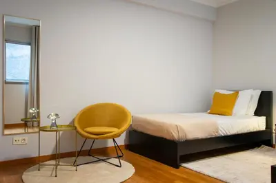 a bedroom with a bed and a yellow chair at Anchored in Carmo by Homie in Câmara de Lobos