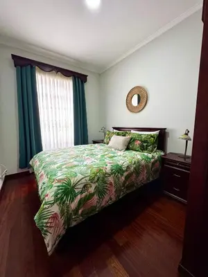 a bedroom with a bed with a tropical bedspread at O Cantinho do Zé - Signature Funchal in Funchal