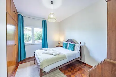 a bedroom with a bed with blue curtains at Vivenda Paz Lobo by YOUR KEY MADEIRA in Gaula