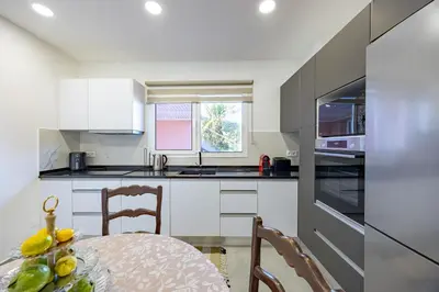a kitchen with white cabinets and a table and chairs at Vivenda Paz Lobo by YOUR KEY MADEIRA in Gaula